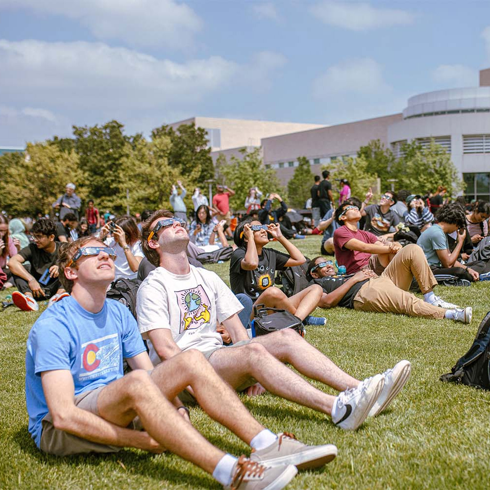 Students wearing special glasses watch the eclipse on campus